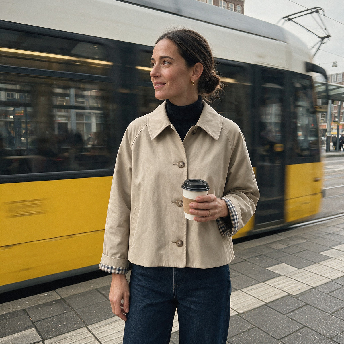 Vrouw bij een tramhalte in jas Noa